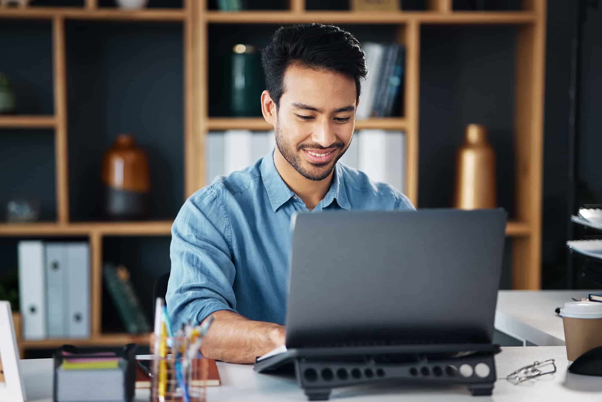 Happy business man typing on laptop in office for startup management, planning and agency. Male worker, smile and computer technology for online project, website and internet research for innovation.