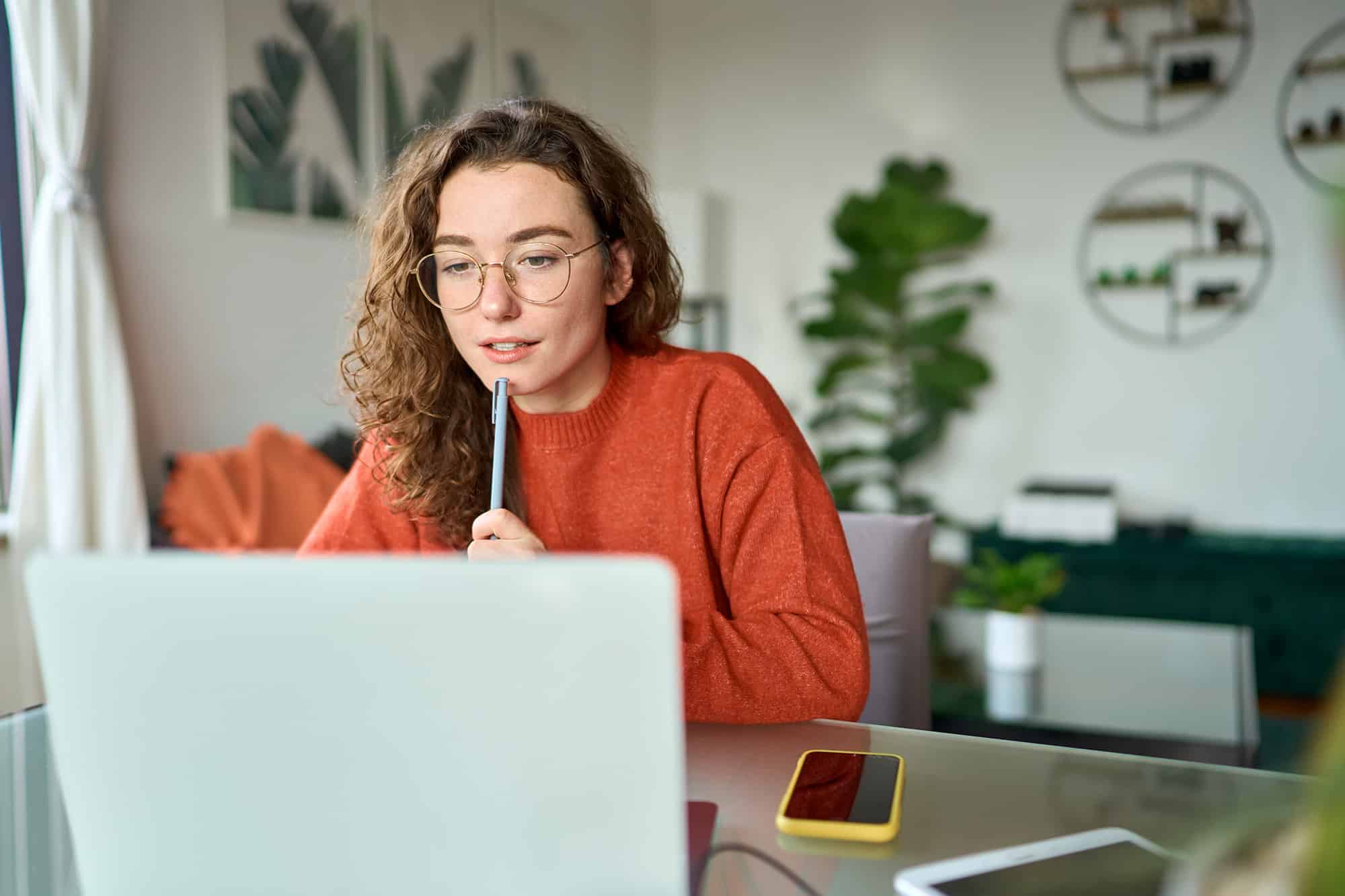 Young girl female student using laptop elearning or remote working at home office looking at computer watching webinar, learning training, studying online seminar or video calling for work meeting.