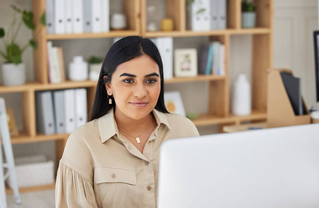 Business, digital or Indian woman typing on computer working on email or online project research. Technology, office feedback or girl journalist writing blog reports or internet articles with focus.