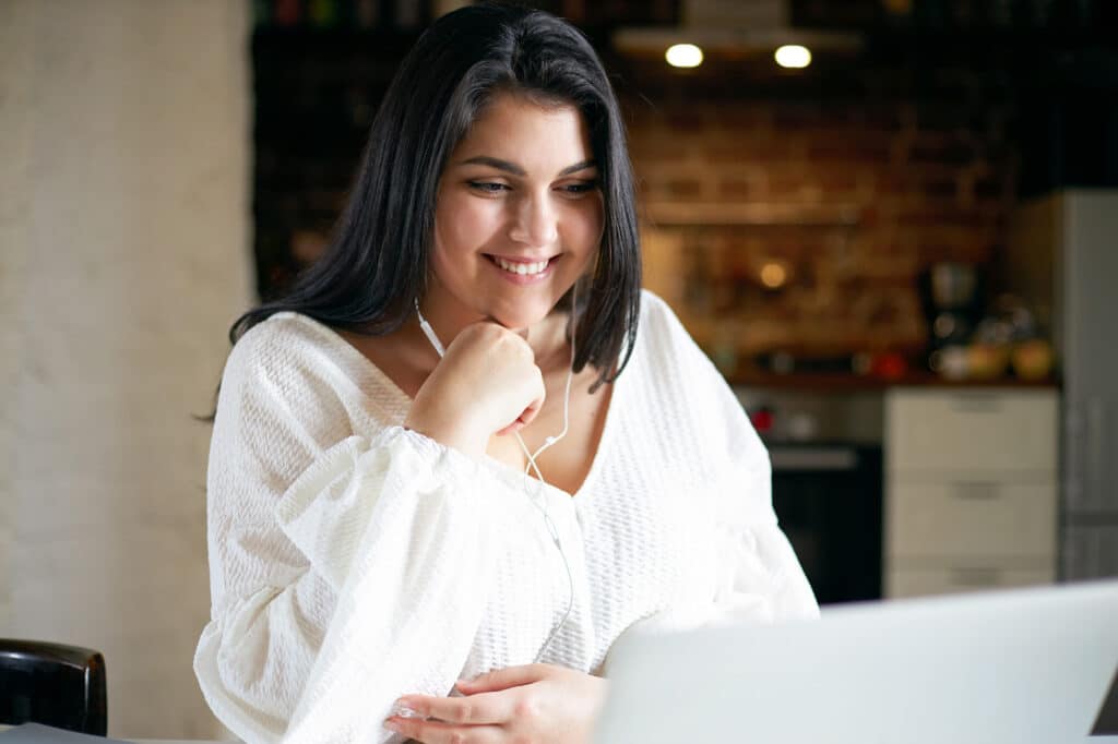 Smiling young woman looking at laptop