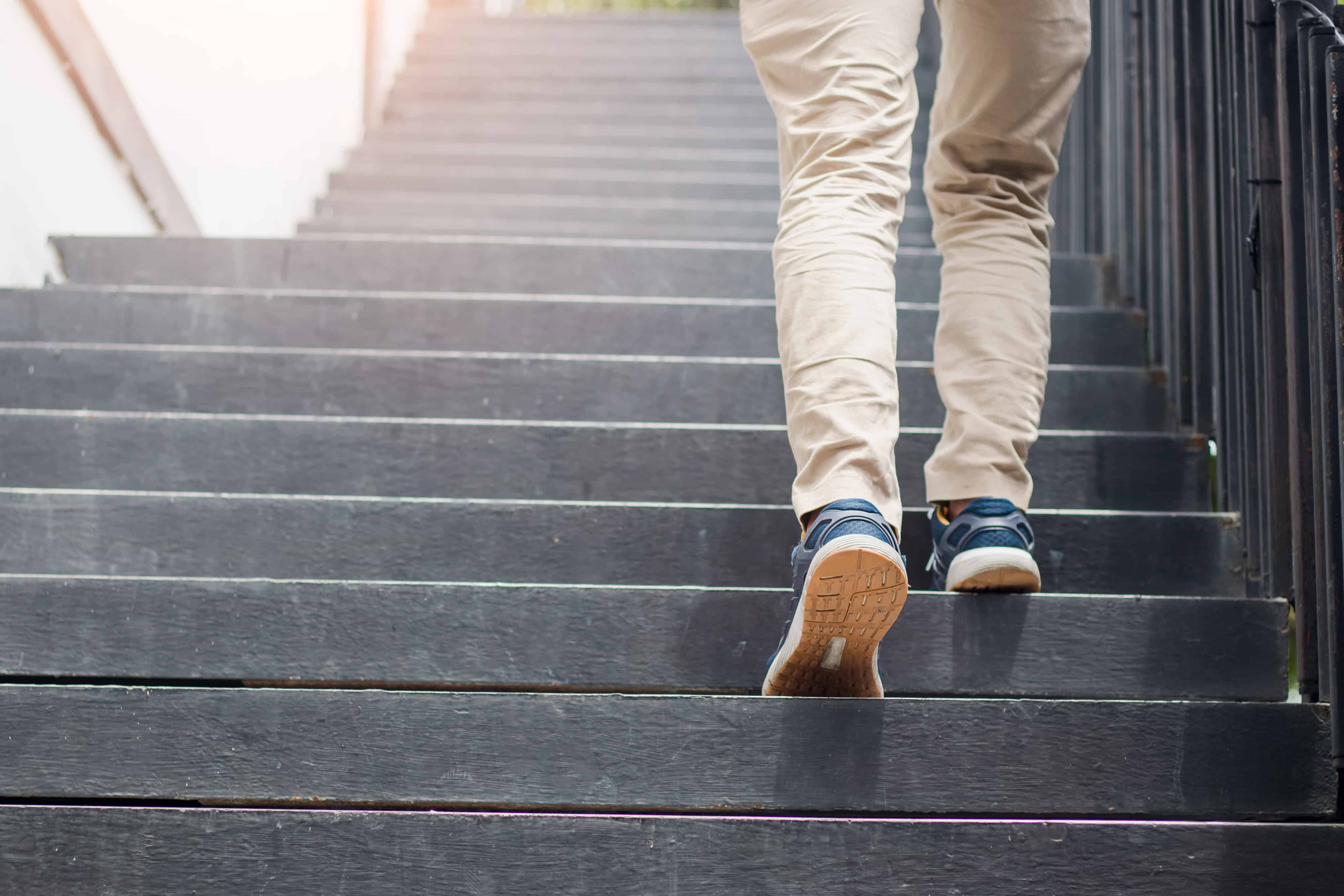 Young man walking up the stairs with sun sport background.step f